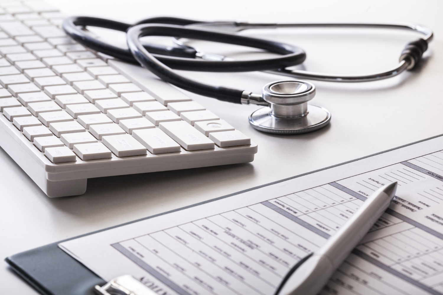 Sur un bureau sont disposés un stethoscope, un style et un contrat symbolisant l'assurance santé.